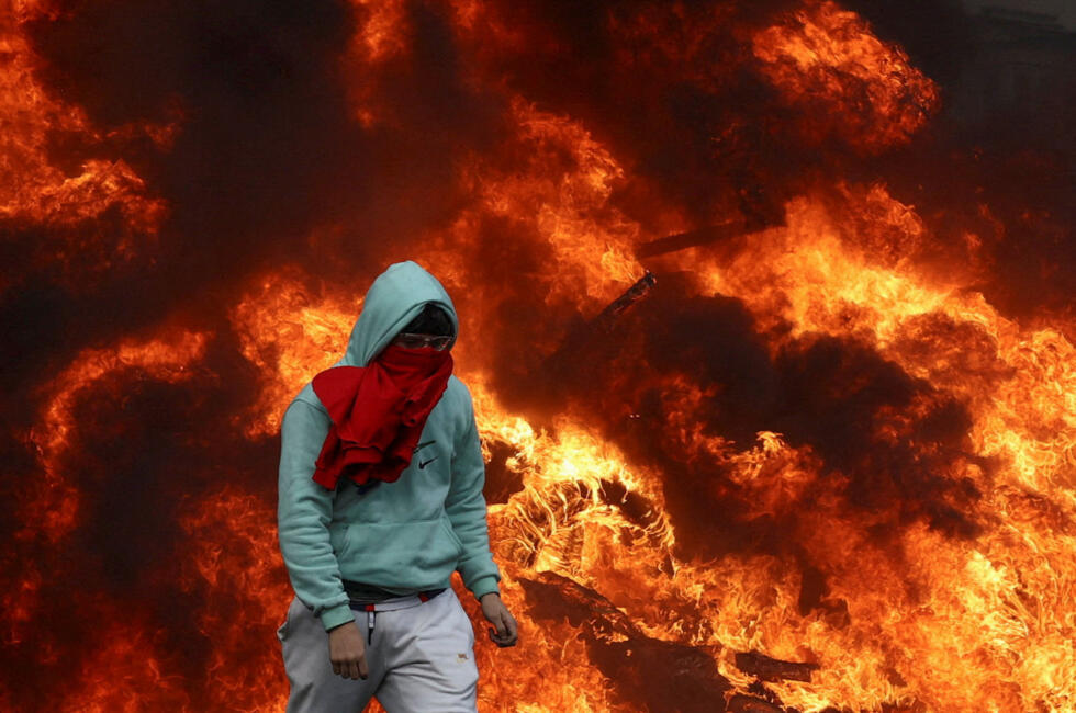 A protester walks past burning tires in a square near the European Parliament, as farmers protest against the EU-Mercosur free trade agreement between the EU and Latin American countries.