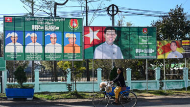 A woman cycles past campaign billboards ahead of Myanmar's general election in Pyin Oo Lwin in Myanmar's Mandalay Region